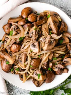 Top down view of mushrooms and onions in a bowl.