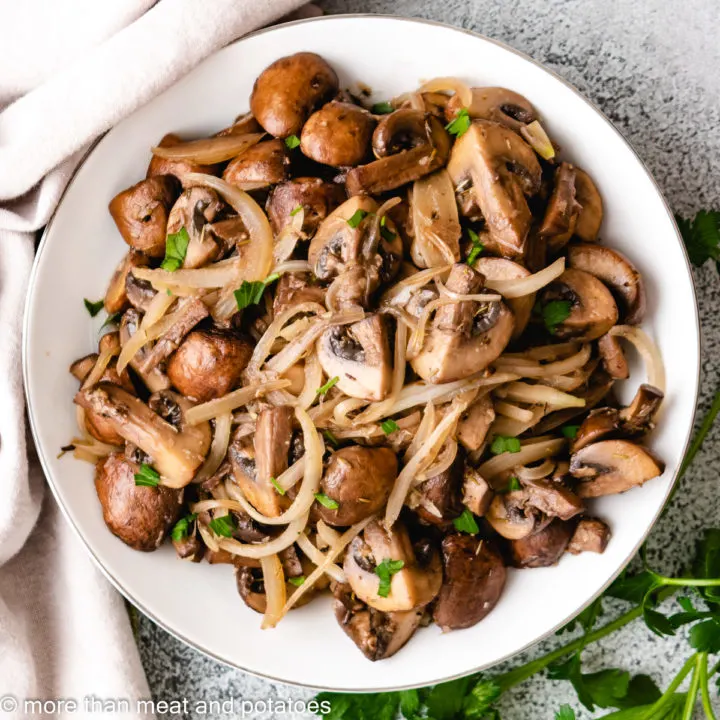 Top down view of mushrooms and onions in a bowl.