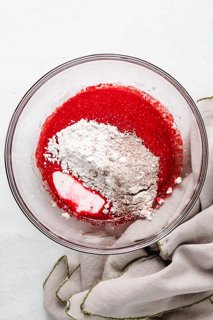 Wet ingredients for red velvet cake with dry ingredients on top.
