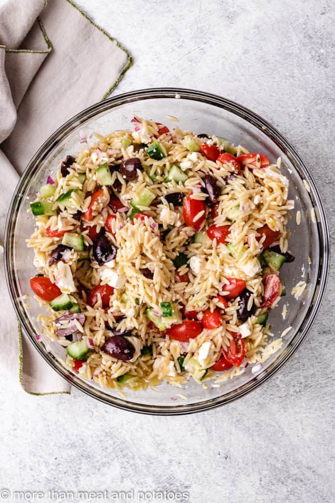 Top down view of greek orzo salad in a glass bowl.