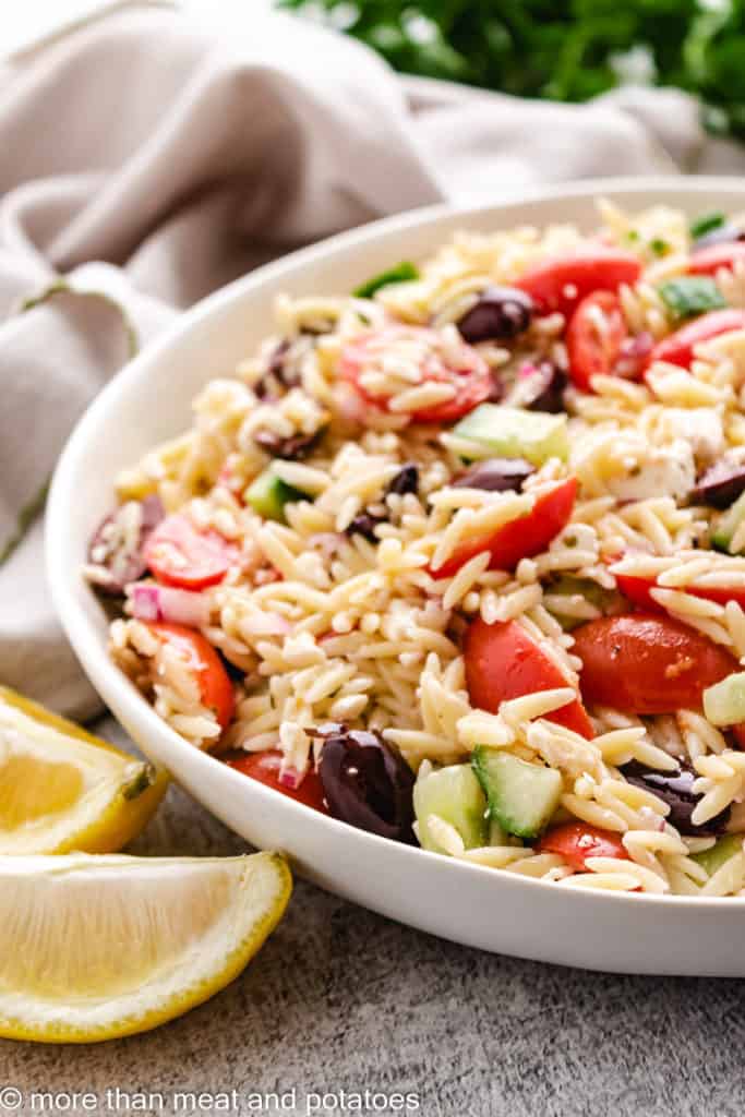 Close up view of orzo pasta salad in a white dish.