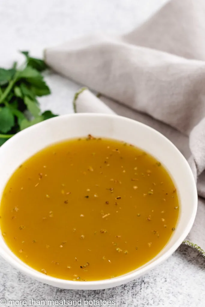 Bowl of vinaigrette dressing with herbs.