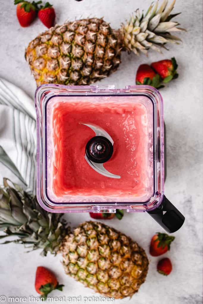 Top down view of a strawberry pineapple smoothie in a blender.