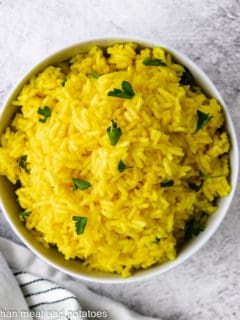 Top down view of yellow rice sprinkled with parsley.