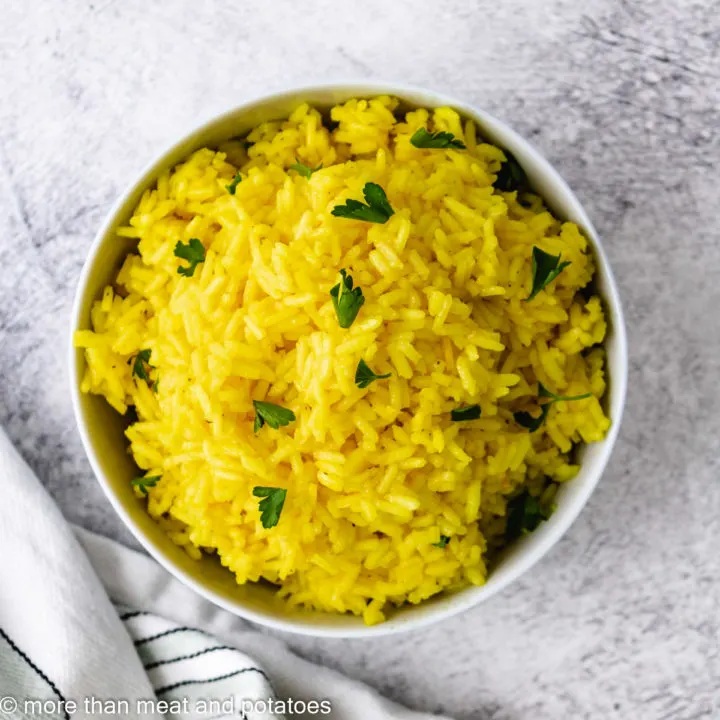 Top down view of yellow rice sprinkled with parsley.