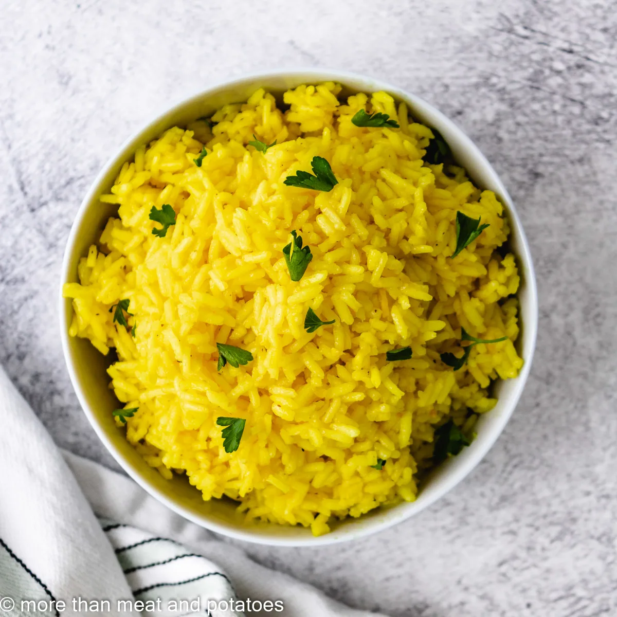 Top down view of yellow rice sprinkled with parsley.