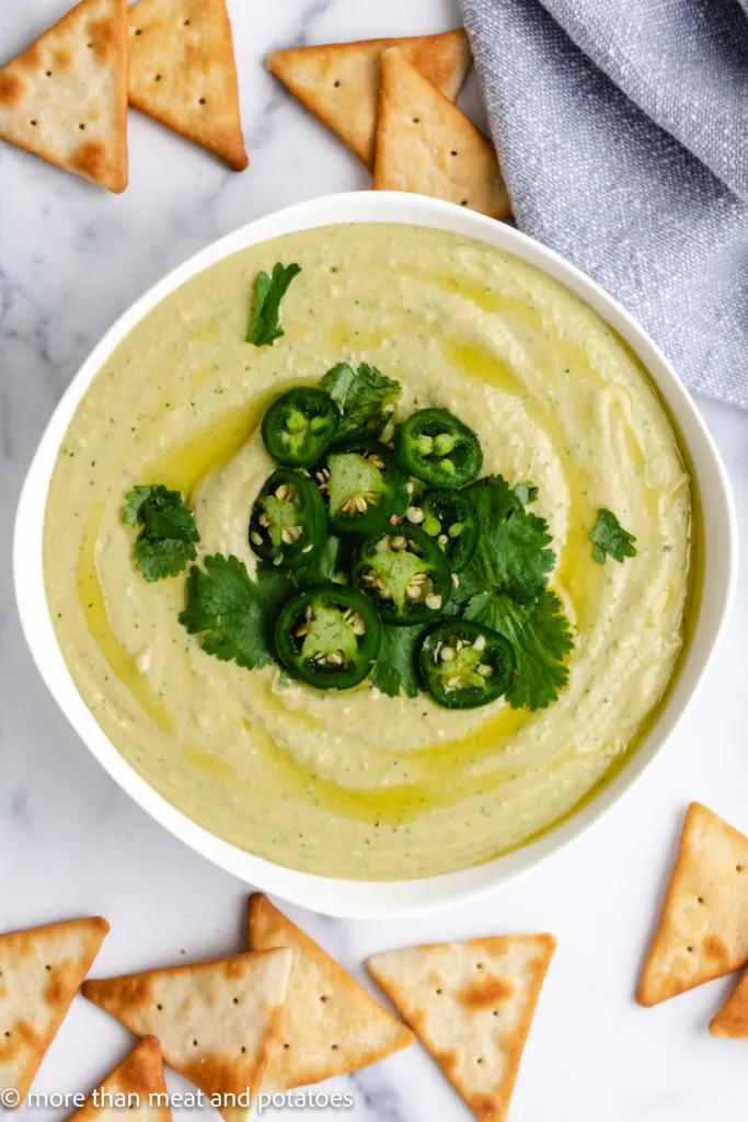 Top down view hummus topped with jalapenos and cilantro.