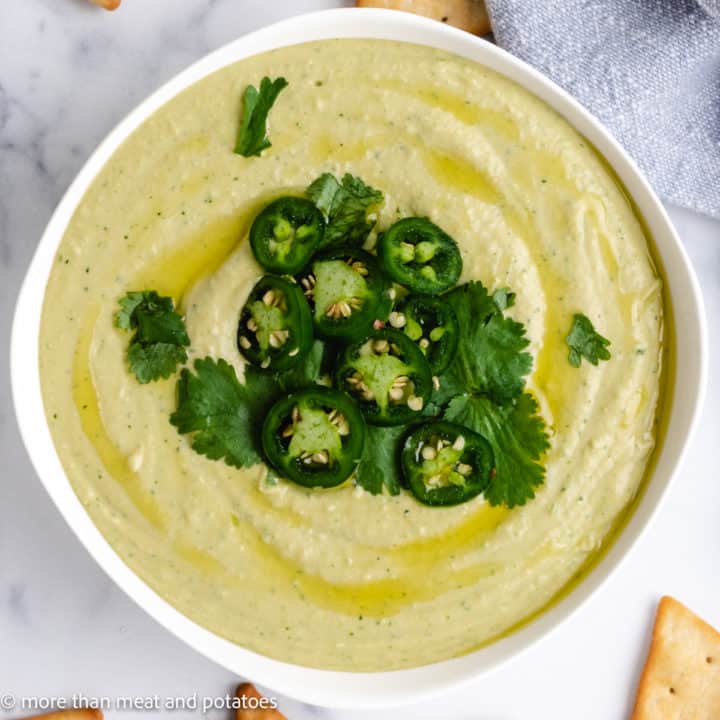 JalapeÑO Cilantro Hummus Top down view of hummus topped with cilantro and hummus.