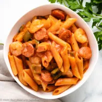 Top down view of pasta with sausage and shrimp in a serving dish.