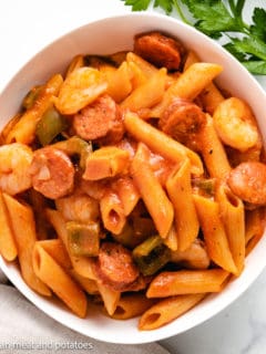 Top down view of pasta with sausage and shrimp in a serving dish.