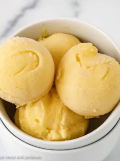 Scoops of pineapple ice cream in a white dish.