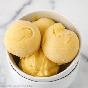 Scoops of pineapple ice cream in a white dish.