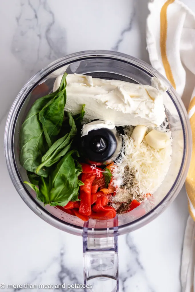 Top down view of the ingredients for roasted pepper dip in a food processor.