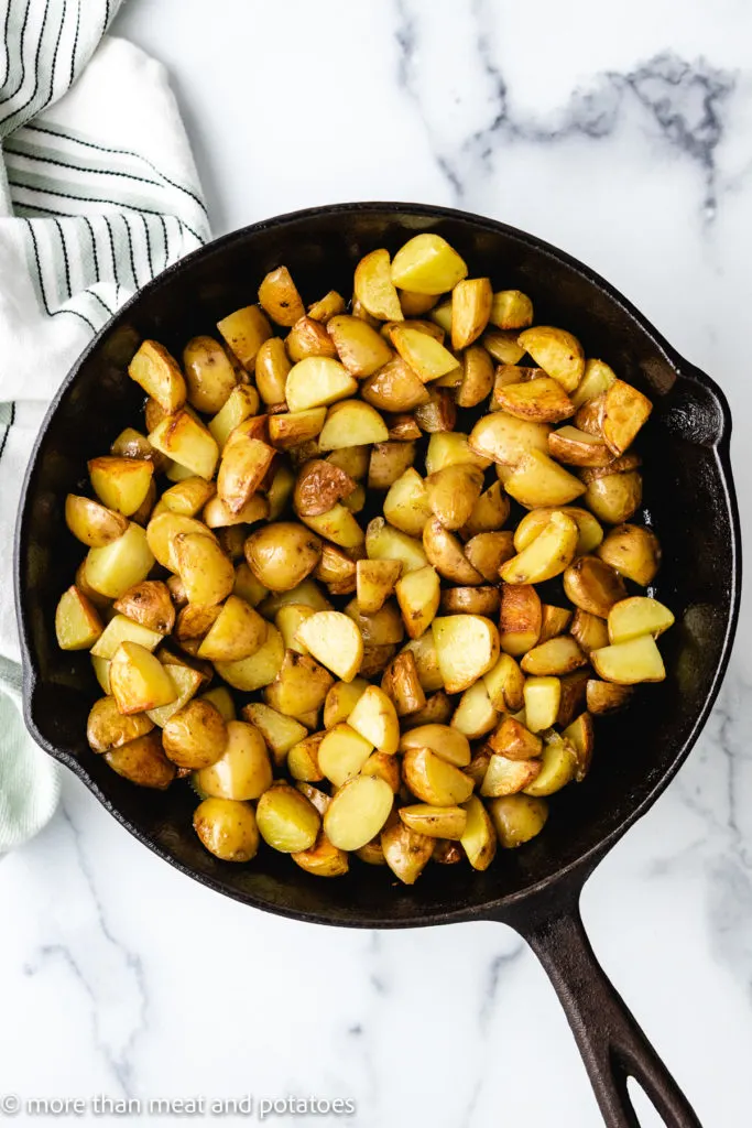 Top down view of potatoes cooking in cast iron.