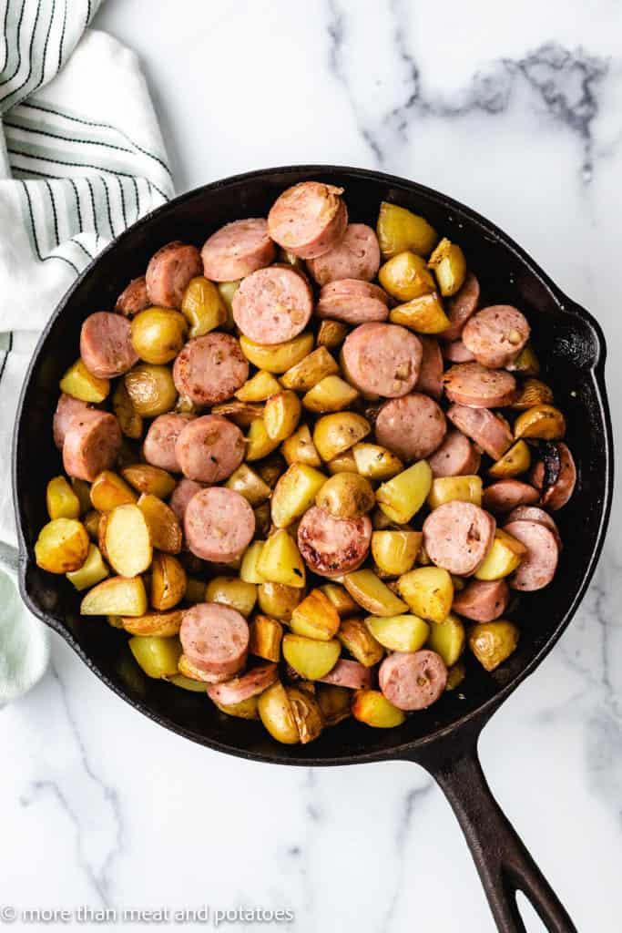 Top down view of sausage and potatoes in a pan.