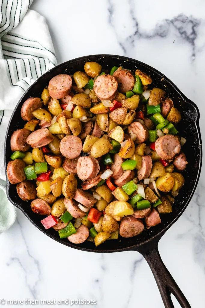 Top down view of potatoes and sausage in a pan.