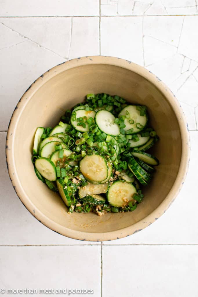 Top down view of sliced cucumbers with asian dressing.