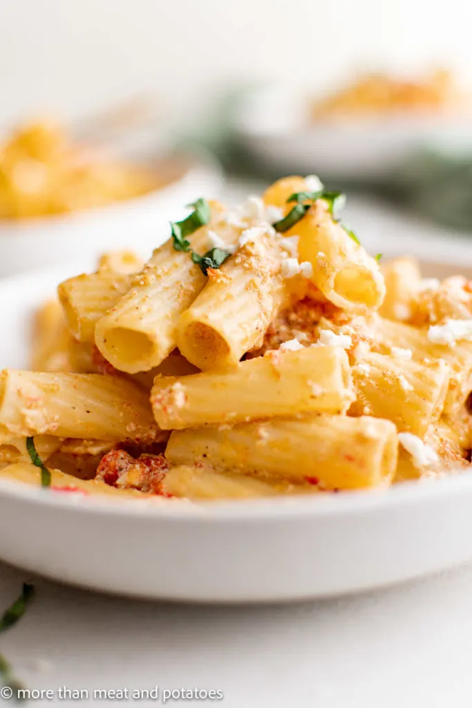 Pile of feta pasta with tomatoes on a serving plate.