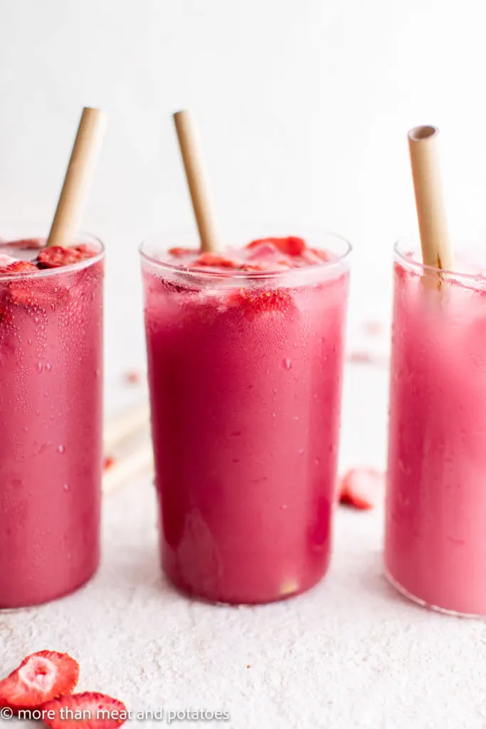 Three glasses of strawberry pink drink with straws.