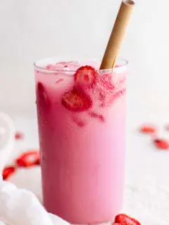Single glass of strawberry pink drink with a straw.