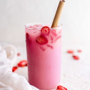 Single glass of strawberry pink drink with a straw.