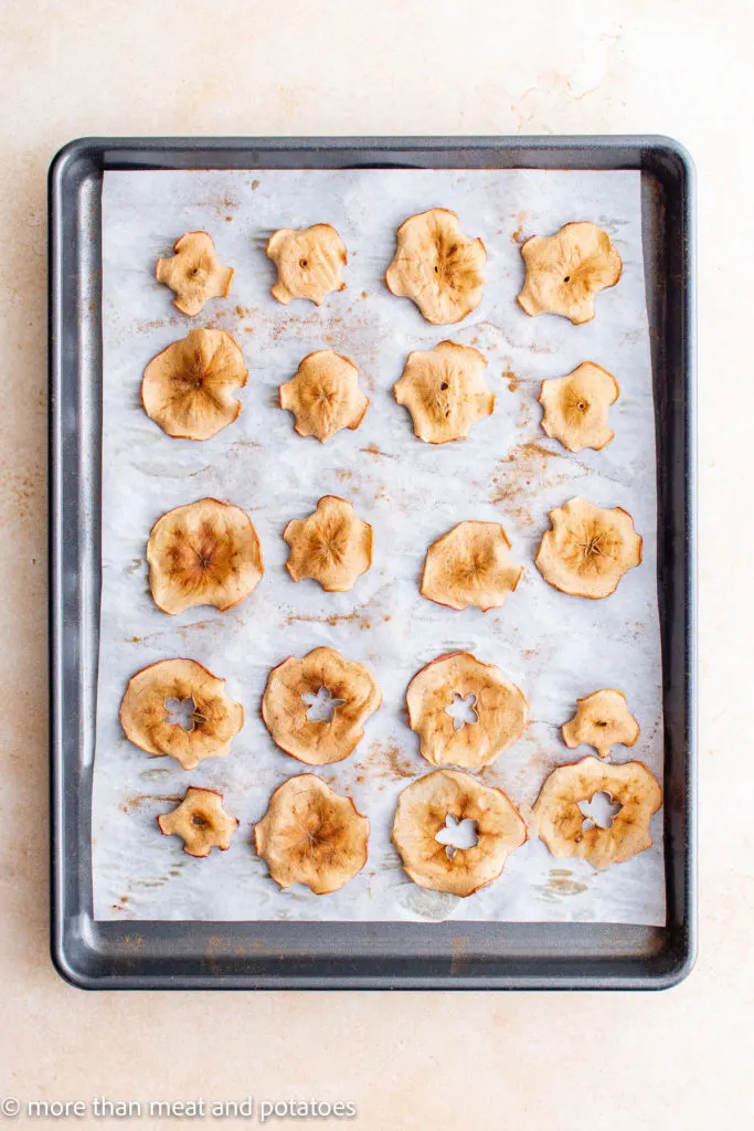 Top down view of apple chips baked on a sheet pan.