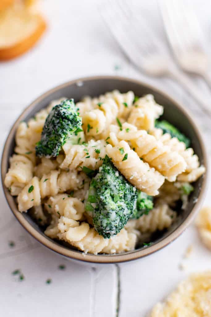 Top down view of pasta with broccoli in a gray bowl.