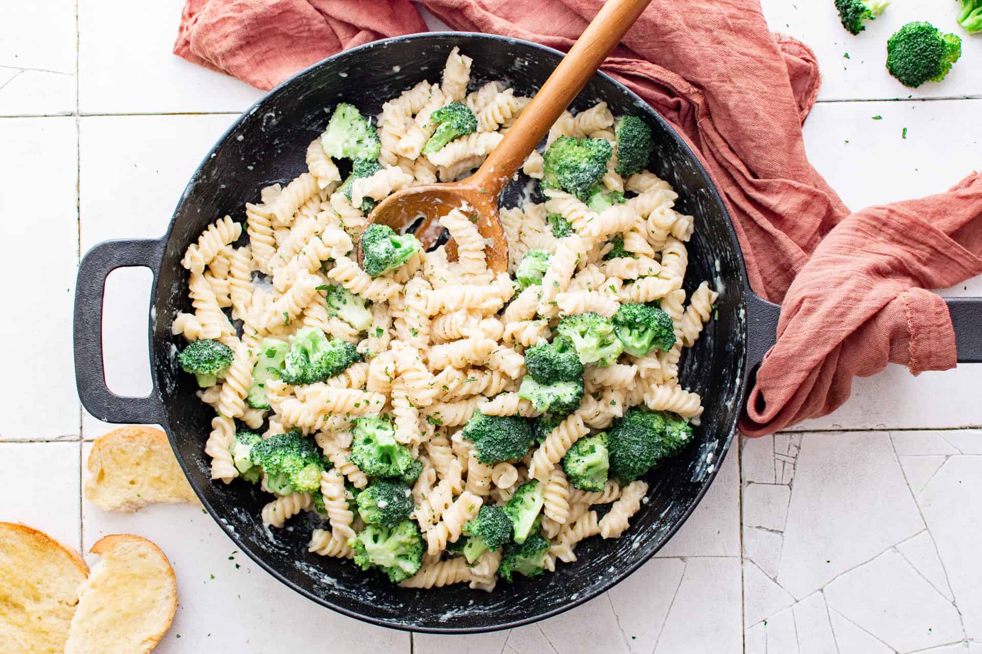 Cast iron pan with broccoli pasta and a serving spoon.