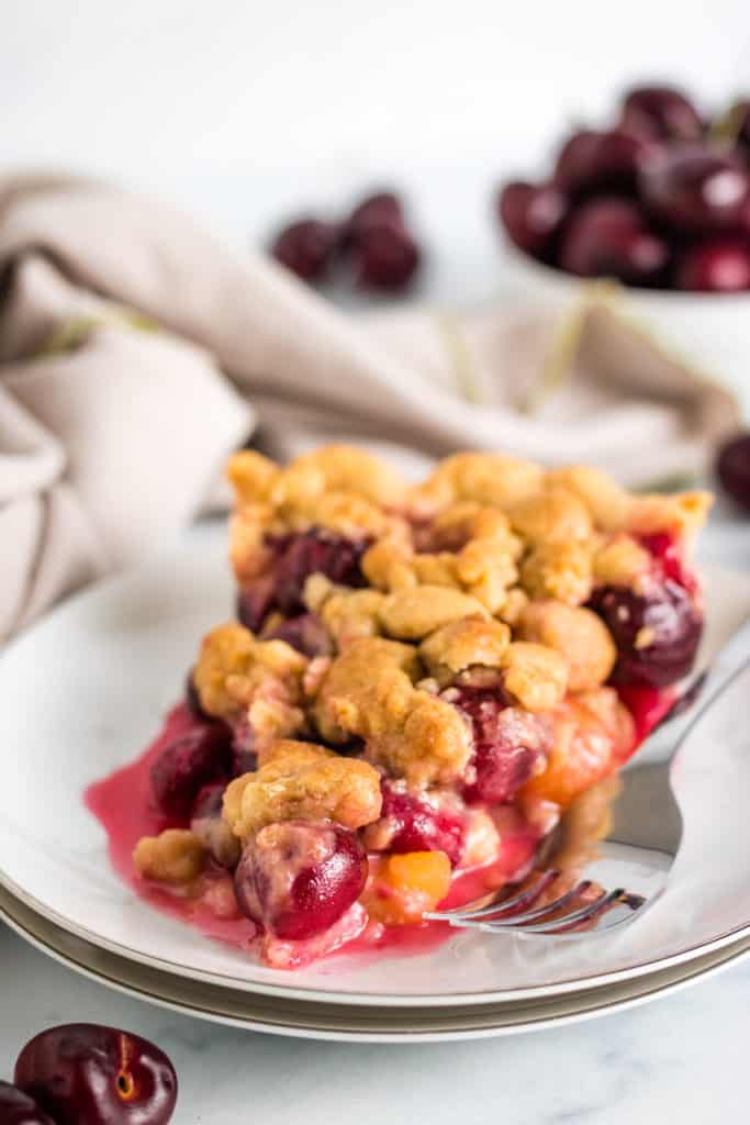 Slice of cherry crumble pie on a plate.