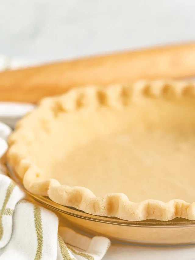 Close up of pie crust with a green and white towel in a dish.