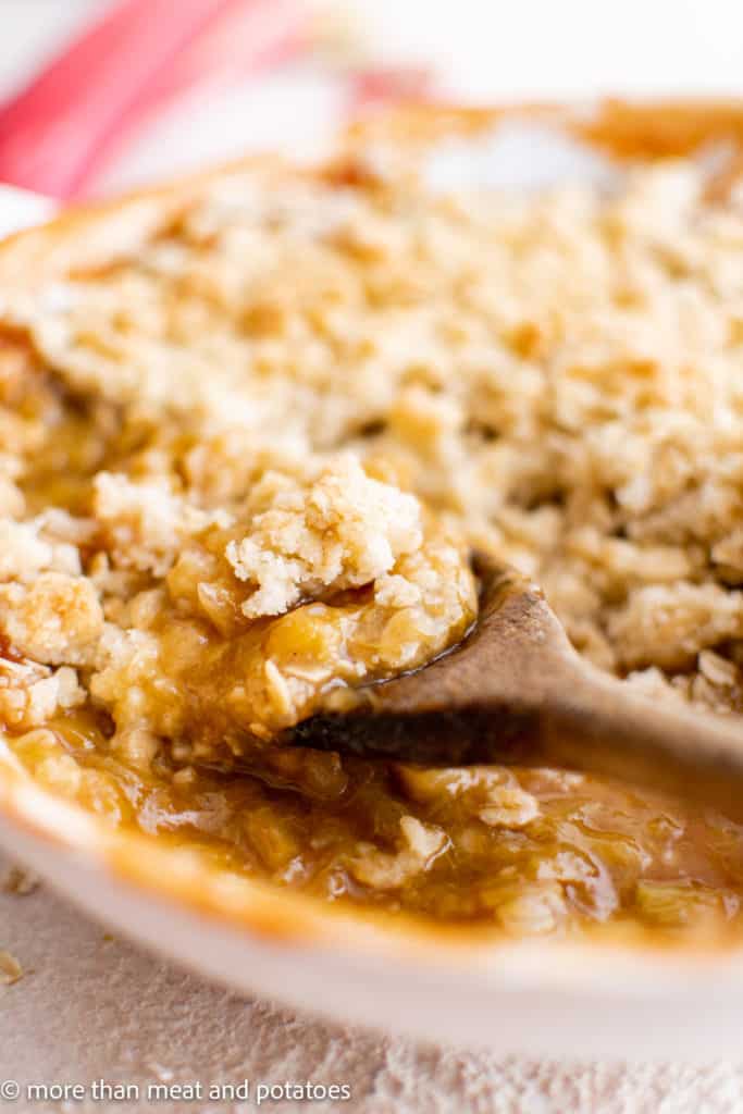 Rhubarb crumble in a pan with a wooden spoon.