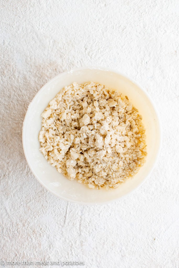 Top down view of oats, flour, sugar, and butter in a bowl.