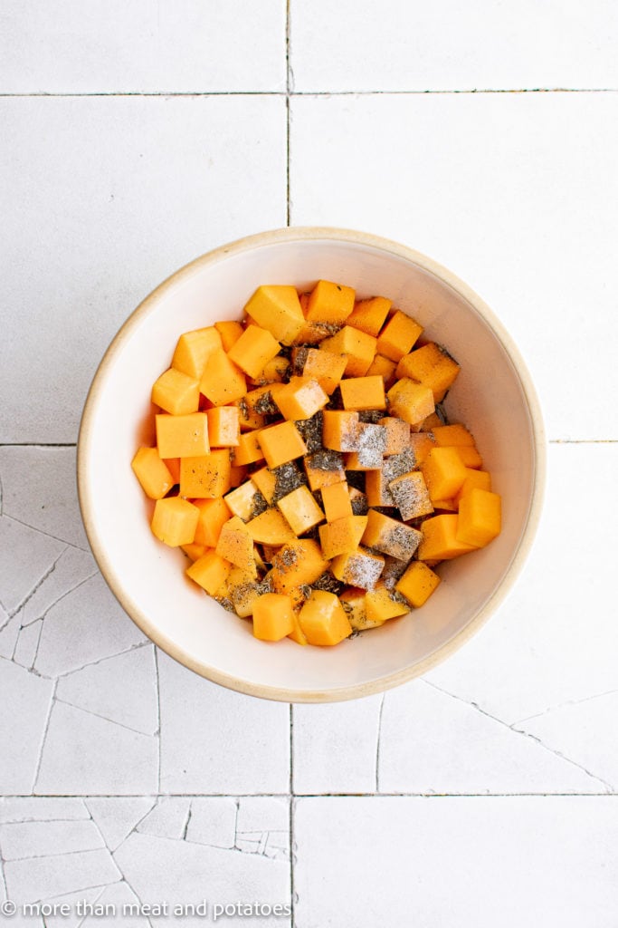 Top down view of butternut squash with seasonings in a bowl.