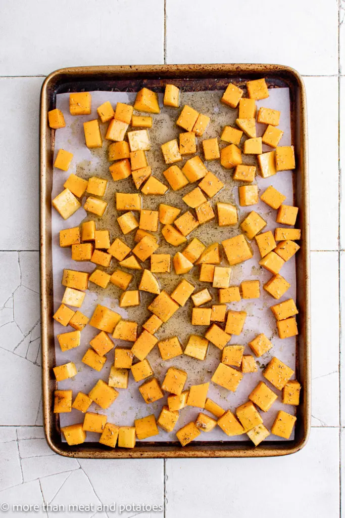 Top down view of unbaked butternut squash on a baking sheet.