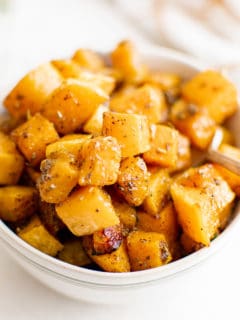 White bowl filled with cooked butternut squash cubes.