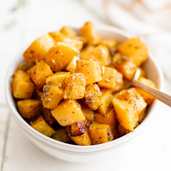 White bowl filled with cooked butternut squash cubes.