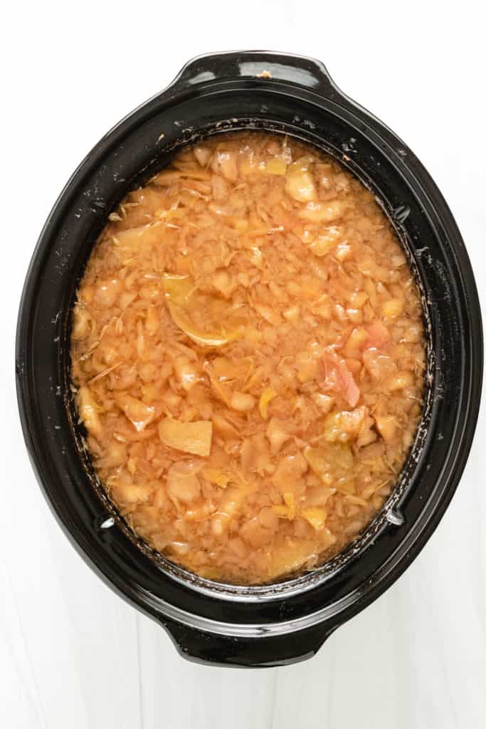 Top down view of mashed apples in a slow cooker.