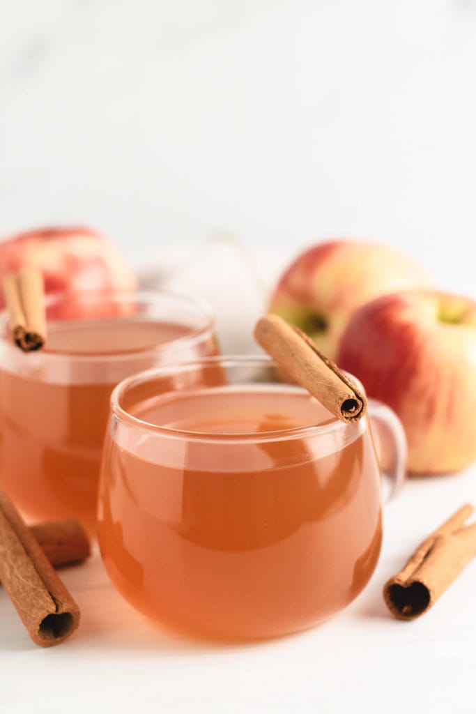 Two mugs of cider with cinnamon sticks.