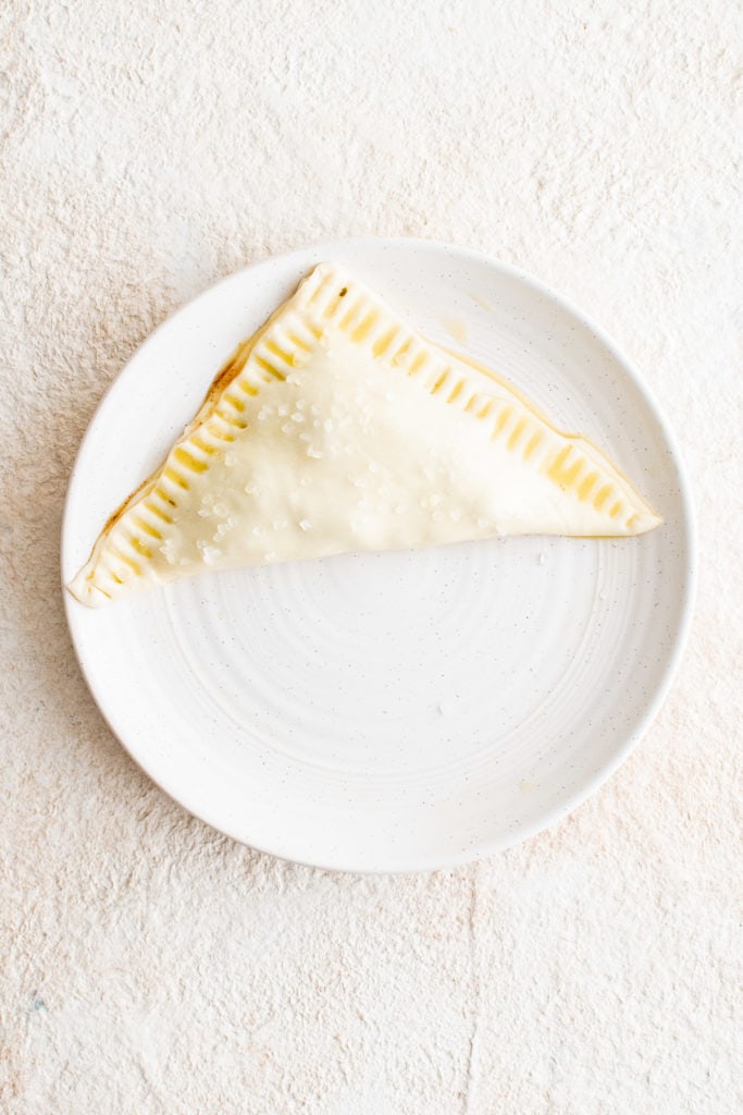 Top down view of a folded apple turnover on a plate.