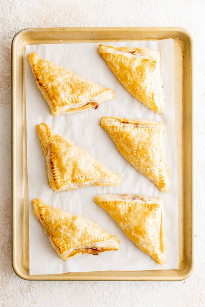 Top down view of apple turnovers on a baking sheet.