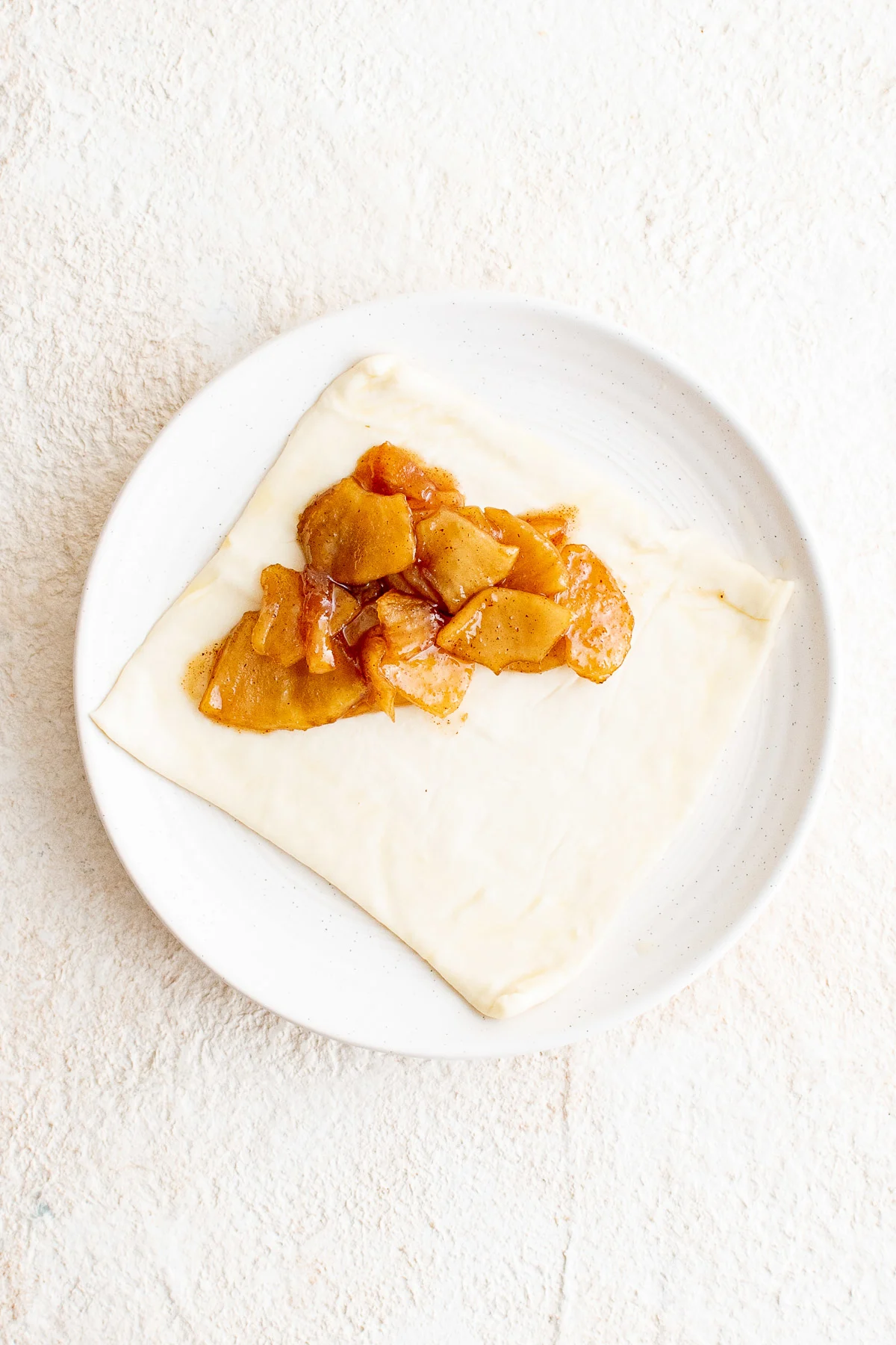 Top down view of apple filling in puff pastry on a plate.