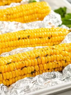 Close up view of four ears of corn on a sheet pan.