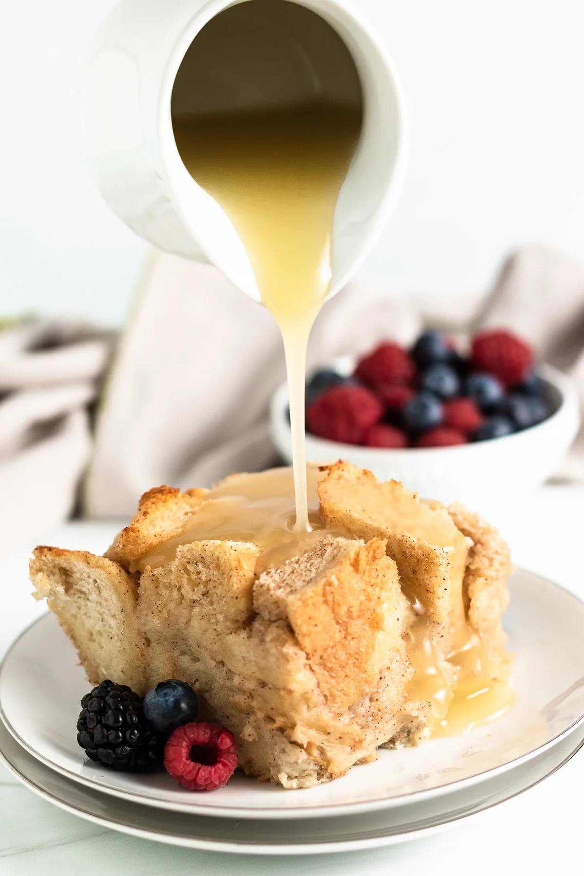 Rum sauce being poured on a plate of bread pudding.