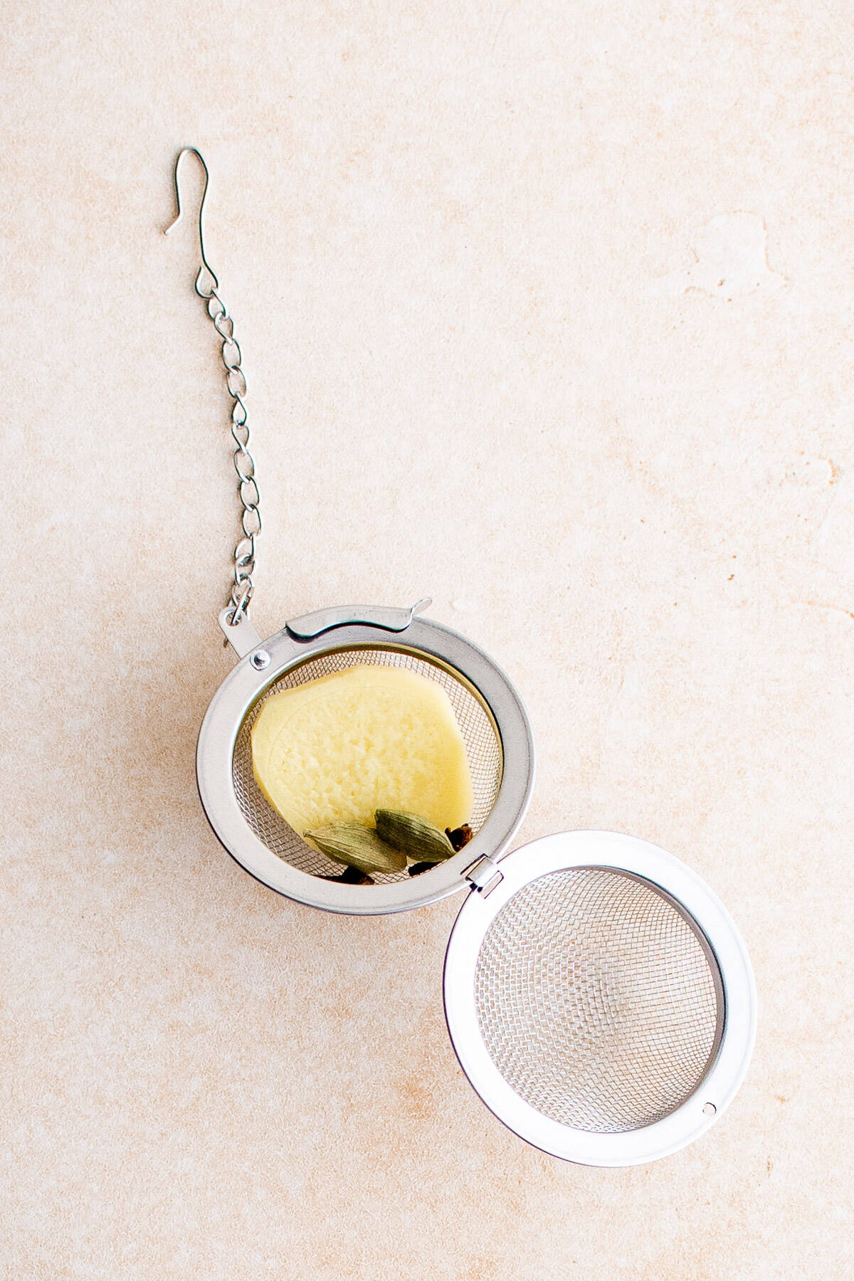 Top down view of an open tea ball with chai latte ingredients.
