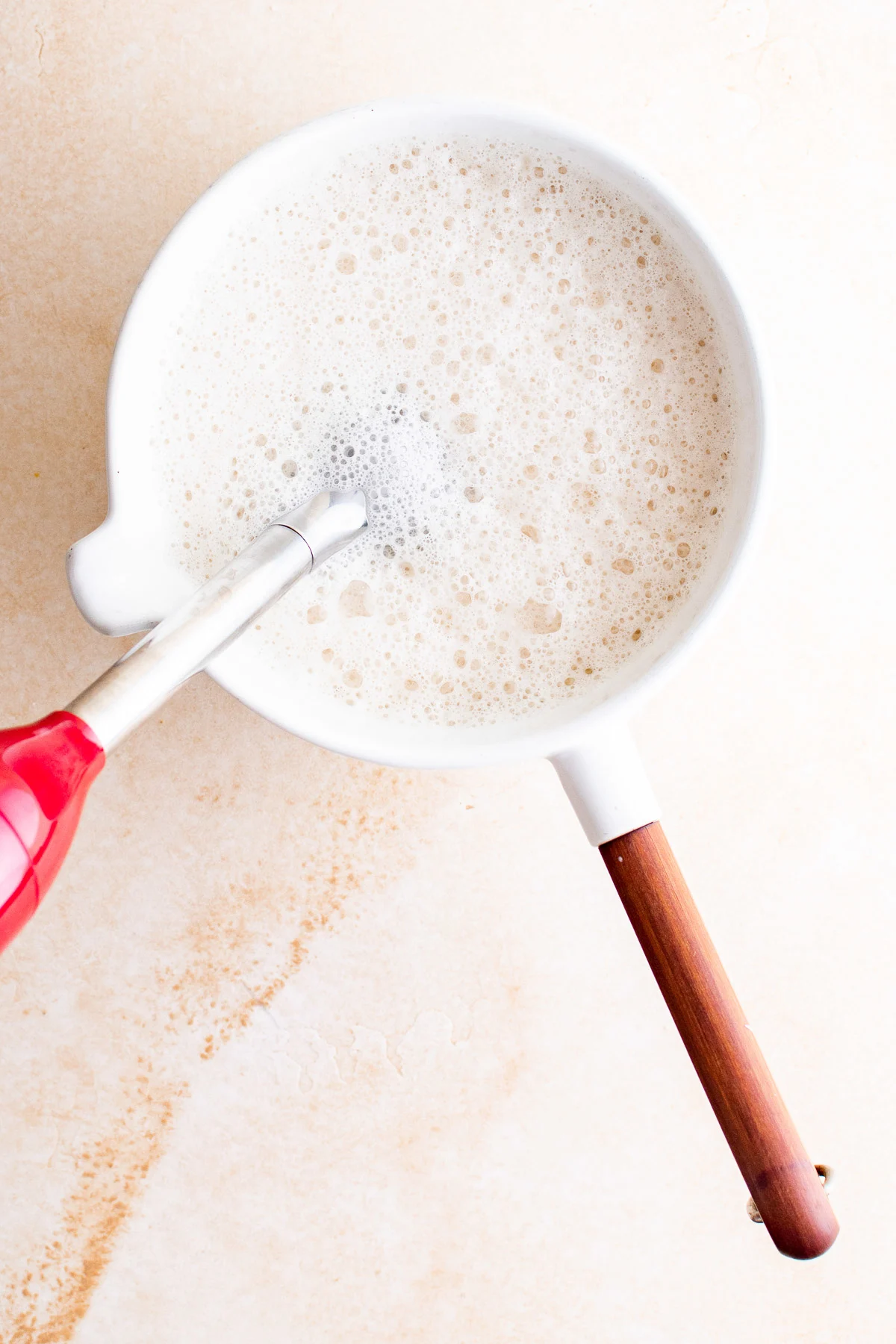 Top down view of milk being frothed in a pan.