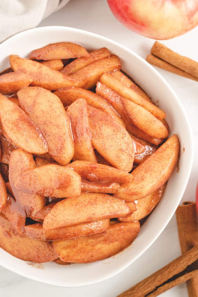 Top down view of cinnamon apples in a white bowl.