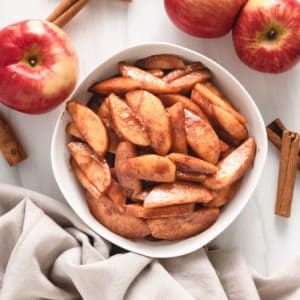 Top down view of cinnamon apples in a white serving dish.