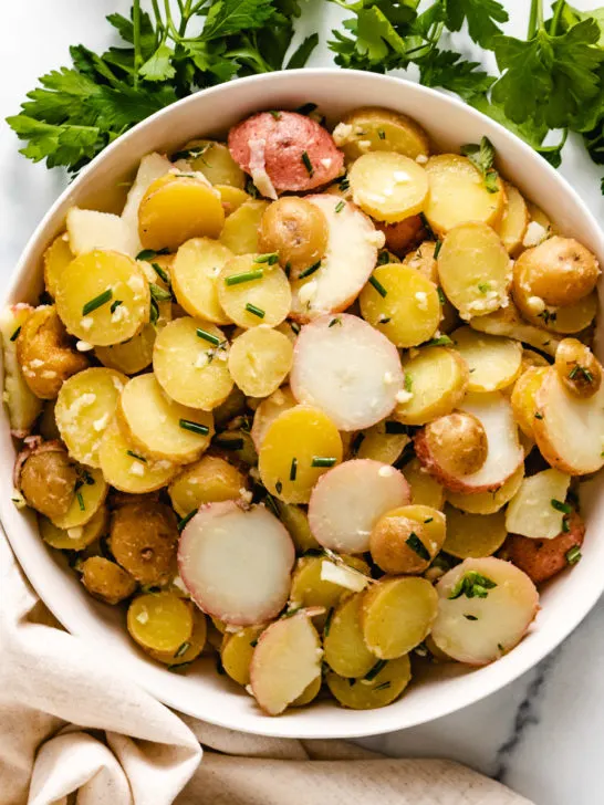 Top down view of potato salad and fresh herbs.