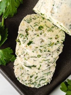 Top down view of herb butter on a black spoon holder.
