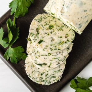 Top down view of herb butter on a black spoon holder.